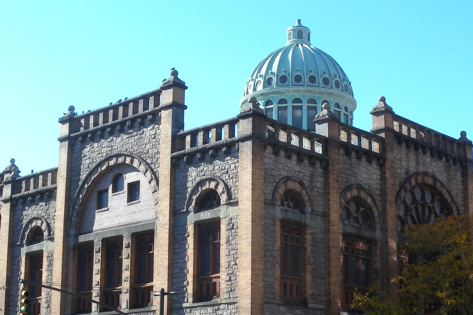 The green copper dome and gold-brick walls of Mount Morris Ascension Presbyterian Church in Harlem under a clear blue sky