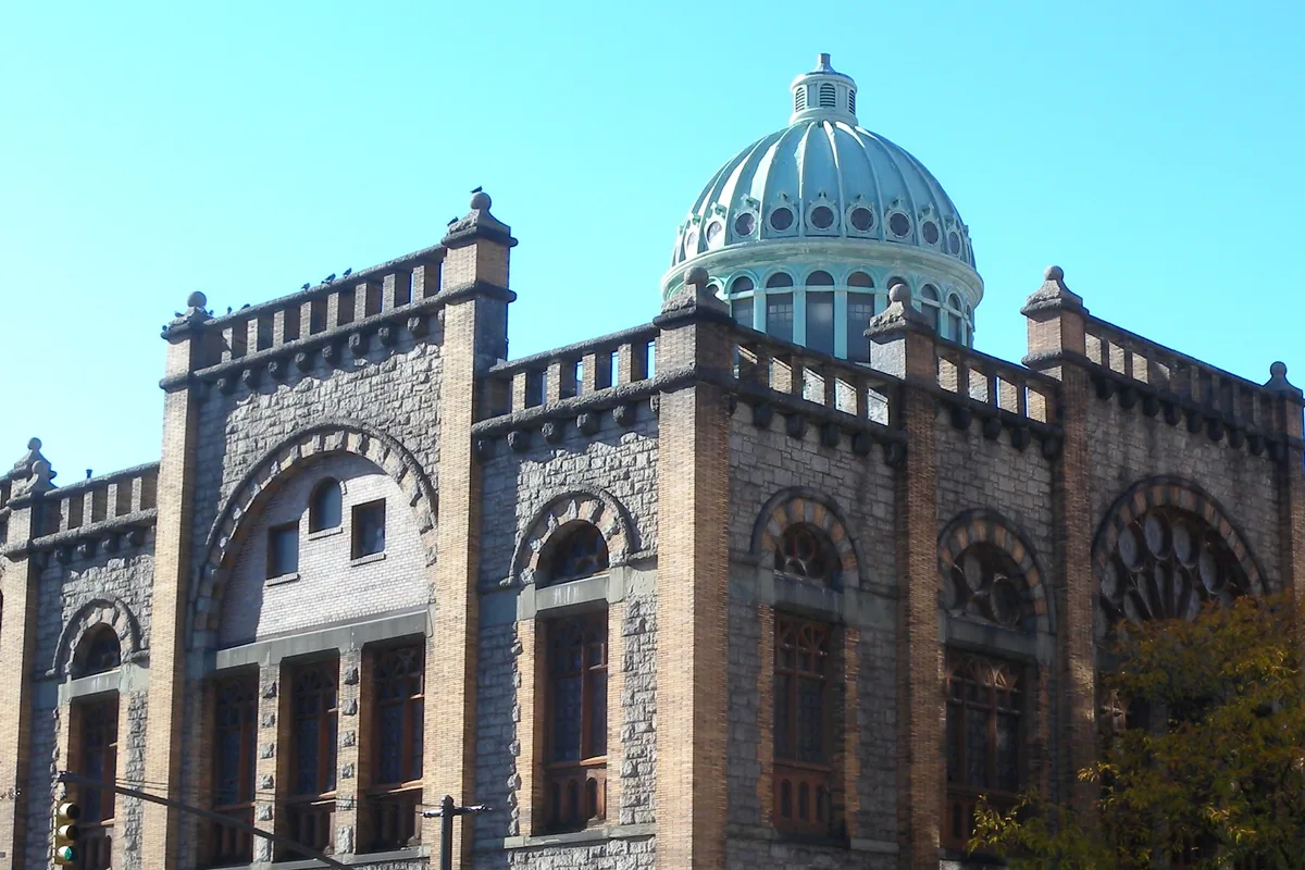 The green copper dome and gold-brick facade of Mount Morris Ascension Presbyterian Church in Harlem under a clear sky